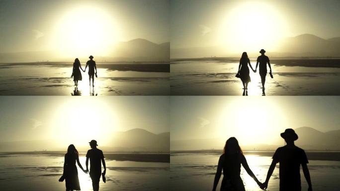 恋爱中的情侣在日落时在海滩上大热天散步