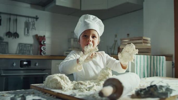 一个美丽的女孩 (孩子) 的肖像，在厨师的衣服做饭和在厨房玩面粉。