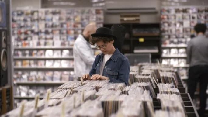 在唱片店用吉他盒浏览黑胶唱片的白人妇女