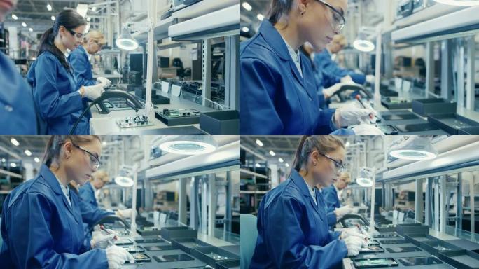 穿着蓝色工作服和防护眼镜的电子工厂女工人正在组装带有镊子和螺丝刀的智能手机。高科技工厂设施，后台有更