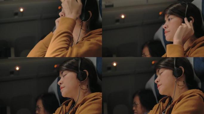 亚洲女性在飞机上在智能手机上选择和听音乐。