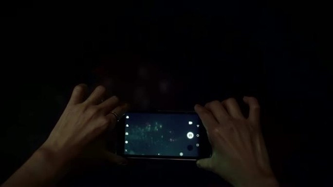 女性用智能手机拍摄烟花