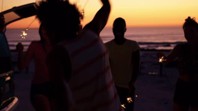 年轻的成年朋友晚上在沙滩上玩火花4k