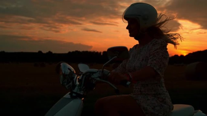 日落时骑踏板车的女人的时间扭曲剪影