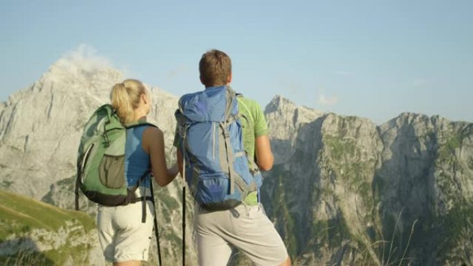 特写: 男性和女性徒步旅行者用电线杆指着山脉。