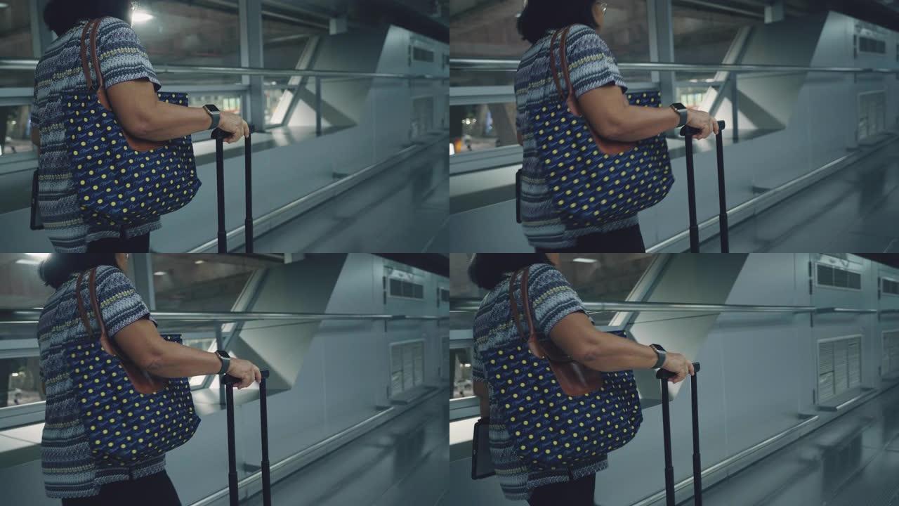 亚洲高级妇女在机场散步和拉行李箱