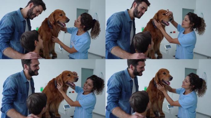 女兽医检查金毛猎犬，而男主人和儿子站在他们旁边微笑着说话