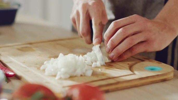 一名男子用锋利的菜刀切碎洋葱的特写镜头。在现代厨房准备健康的有机餐。天然清洁饮食和健康的生活理念。