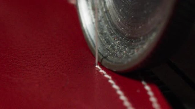 根据意大利的传统，鞋匠使用缝纫机缝制红色皮革的特写镜头。