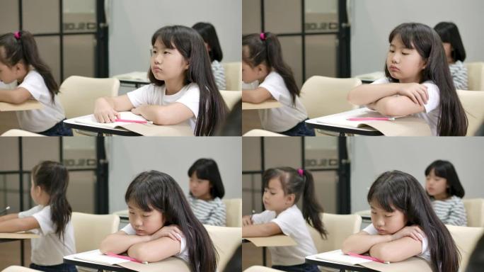 女孩因为学习太多而睡着了。睡在教室桌子上的亚洲女学生。