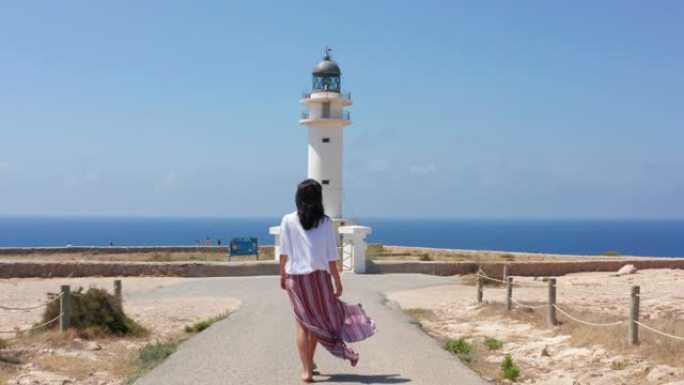 暑假期间，年轻女性游客的慢动作将前往西班牙福门特拉岛皮拉尔德拉莫拉附近的灯塔