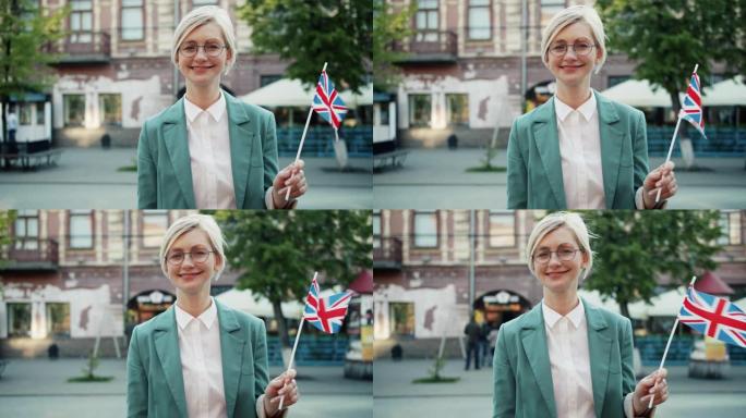 戴着眼镜的迷人女孩在户外举着英国国旗的慢动作