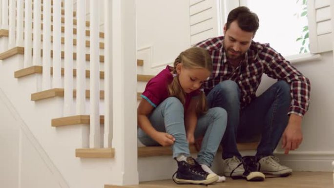 父亲在舒适的家中帮助女儿在楼梯上穿鞋4k