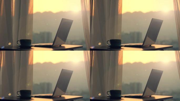 日落时分，木桌上的笔记本电脑靠窗户