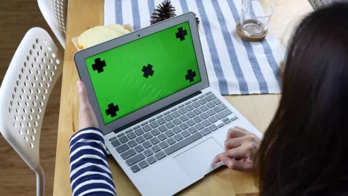 女人看着绿色屏幕的笔记本电脑的后视图