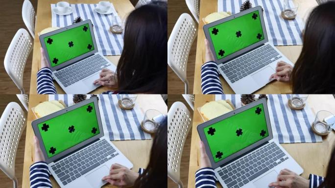 女人看着绿色屏幕的笔记本电脑的后视图