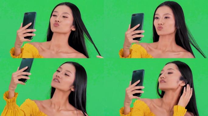 欢快的黑人女性手持智能手机拍照的肖像在绿色背景上孤立的前摄像头上拍摄自拍享受周末假期。技术概念。绿屏