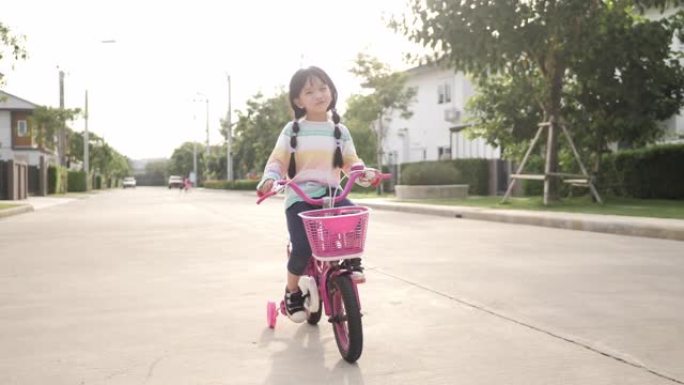 亚洲小女孩在街上骑自行车。