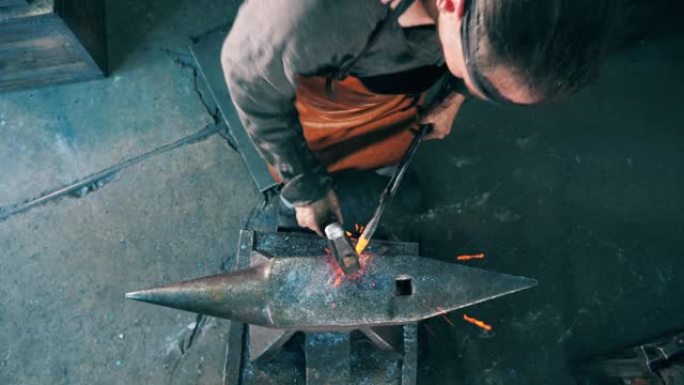 铁匠在铁砧上塑造一把刀，用锤子击打它。