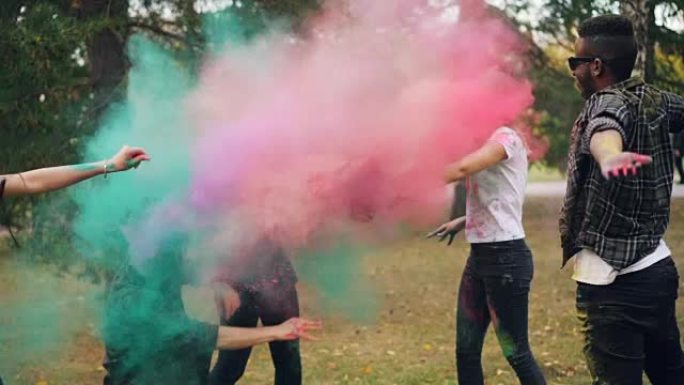 快乐的学生慢动作在洒红节上互相扔五颜六色的粉末涂料，在公园户外笑着享受快乐的传统。