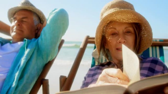 活跃的白人女性在海滩上看书的前视图4k