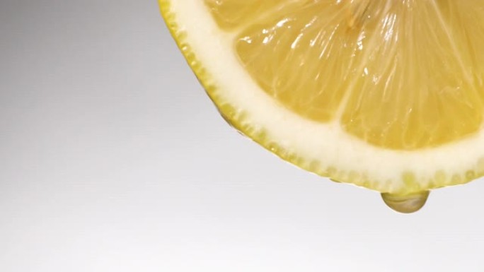 慢动作: 柠檬片上的许多液体掉落在白色上