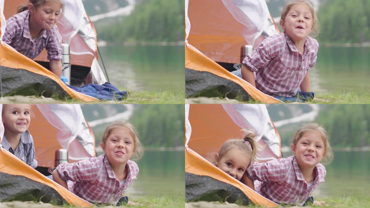 两个姐妹在湖边露营，他们喜欢在帐篷里玩耍，周围是大自然。