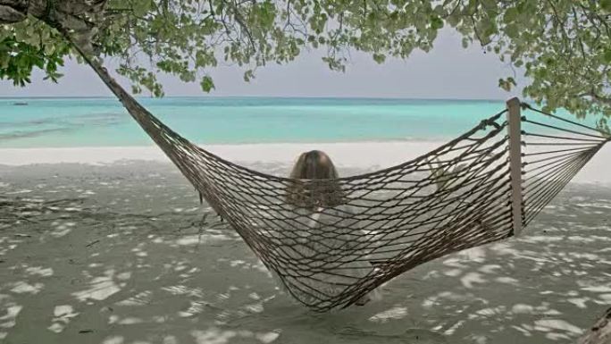 宁静的女人女士在马尔代夫宁静的热带海洋海滩的吊床上