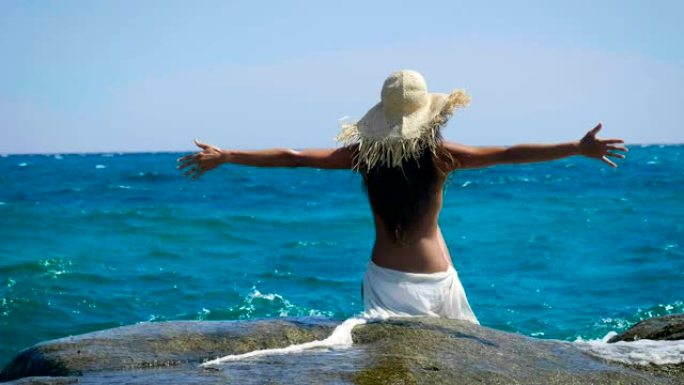 一个女人坐在木墩上的肖像，看着大海感到自由，海蓝色的水和天空的背景。
