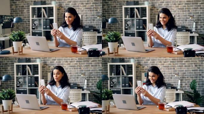 情绪激动的年轻女子在办公室用智能手机进行在线视频通话