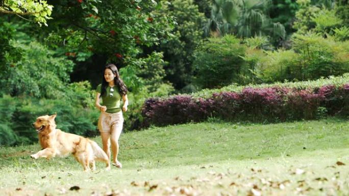 年轻的亚洲女子带着她的狗在户外跑步