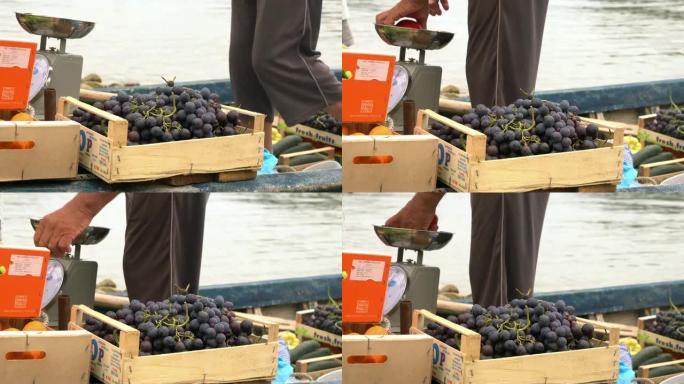 Man女士带着新鲜的葡萄，苹果和秤在船上