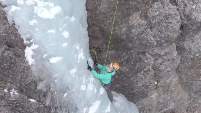 无人机: 女登山者在攀登冰冷的瀑布时放置冰镐。