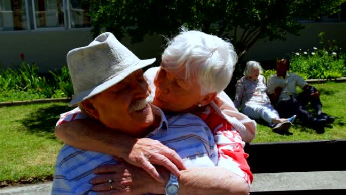 活跃的高加索老年夫妇在养老院4k花园中互相拥抱的前视图