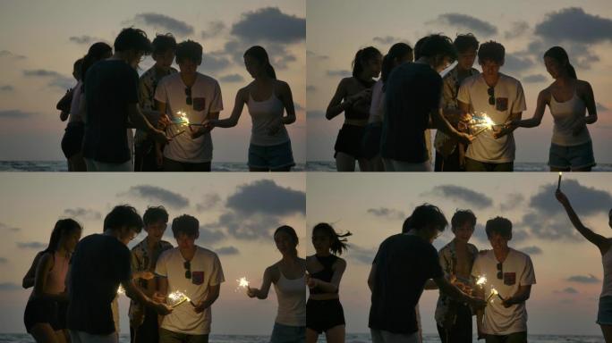 一群朋友在海边的夜间聚会上玩得开心，手里拿着孟加拉的烟火。青少年在海滩上放烟花聚会。慢动作镜头。
