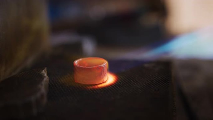 使用喷灯在工作室里在戒指上工作的女性珠宝商的特写镜头