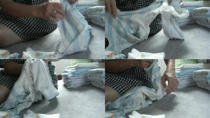 妈妈在家手工折叠婴儿服装概念
