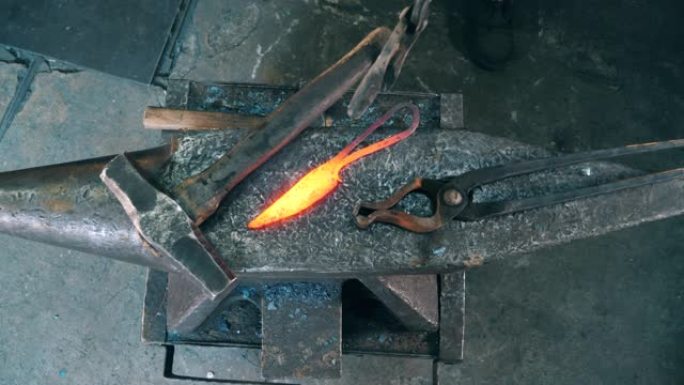 工作铁匠把一把热刀放在铁砧上。