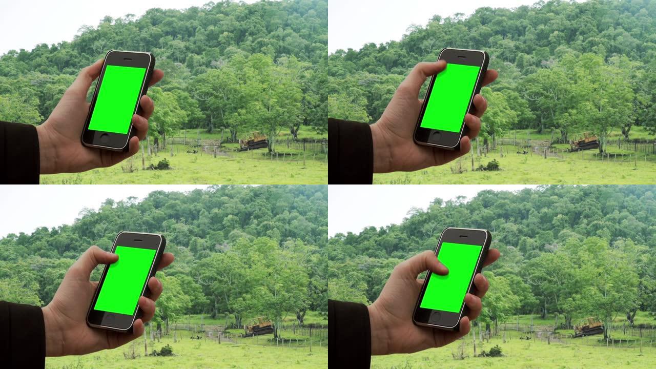男子在丛林中使用带有绿屏的旧智能手机。