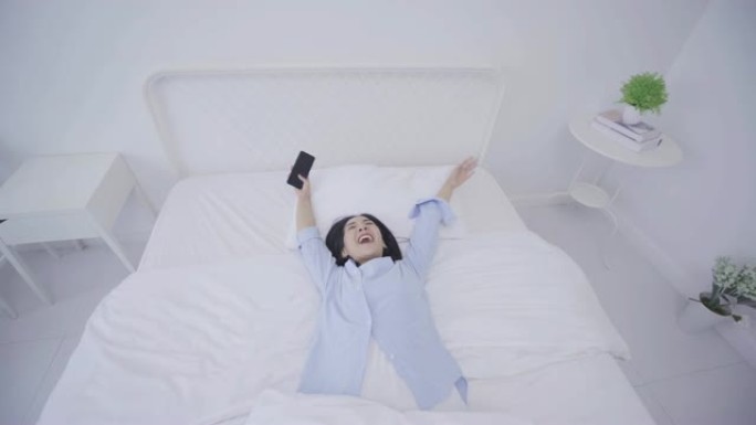 4k分辨率美丽有趣的亚洲女人使用智能手机躺在床上