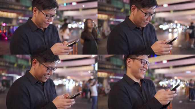 亚洲男子在泰国曼谷姚瓦拉特路等出租车时使用智能手机