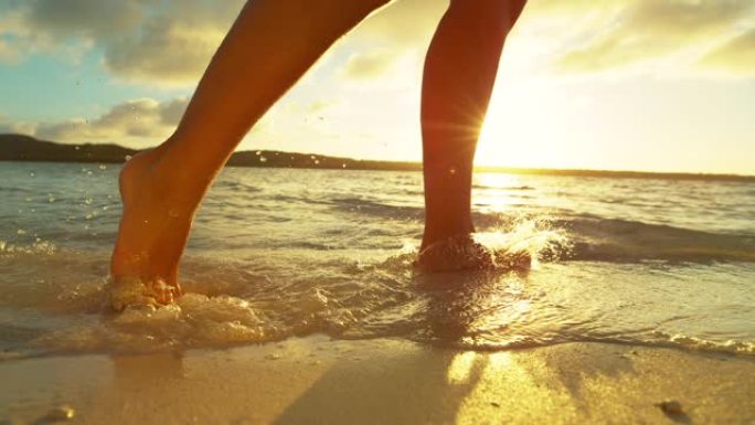 慢动作: 女孩在沙滩上奔跑时溅起玻璃状的海水。