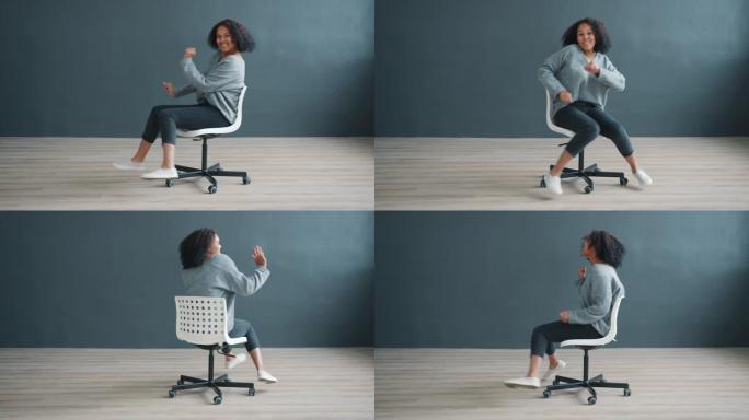快乐的非洲裔美国女人坐在办公椅上跳舞玩得开心