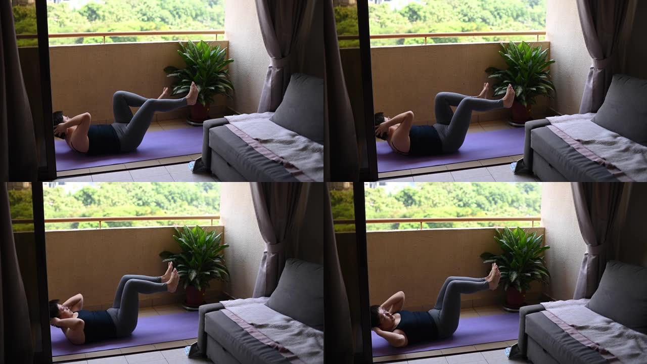 在马来西亚，一名亚洲中年妇女在限制行动期间在家阳台上练习瑜伽