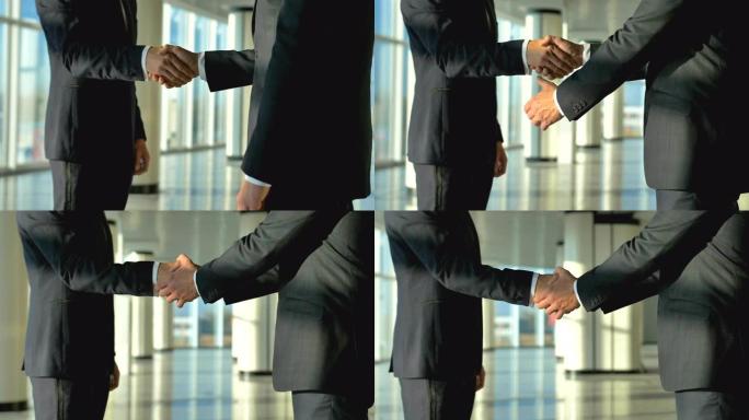 两位商务人士在办公大厅握手。慢动作