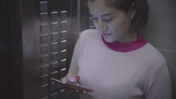 在电梯中使用智能手机的年轻女子