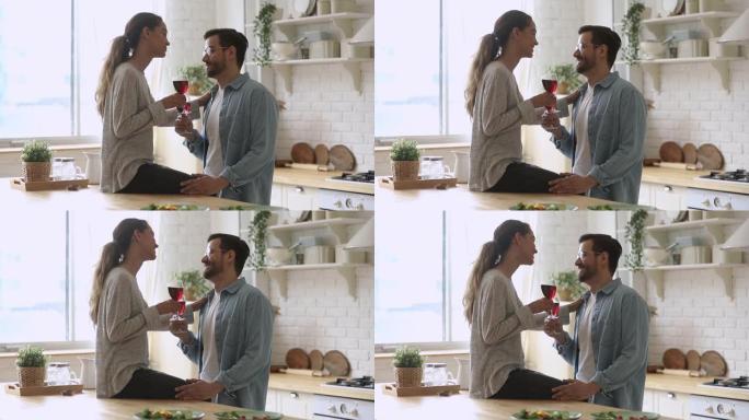 幸福的年轻夫妇拿着眼镜在厨房里说话
