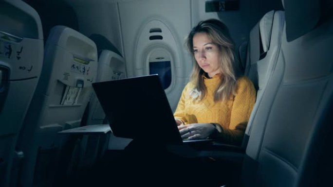 晚上与一位女士使用笔记本电脑的机舱