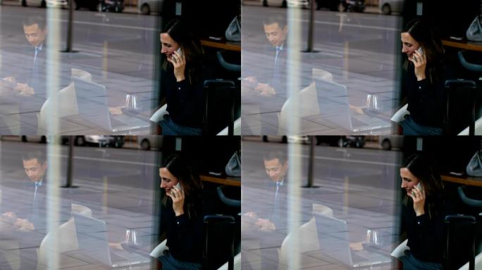 美丽的高加索女商人在手机上聊天并使用笔记本电脑的侧视图