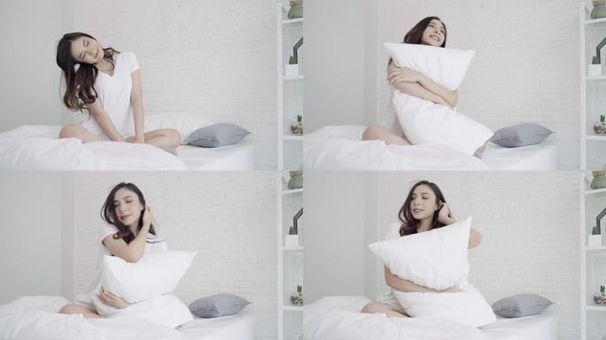 快乐美丽的亚洲女人醒来，微笑着在卧室的床上伸展双臂。年轻的亚洲女性在家使用放松时间。生活方式女人在家